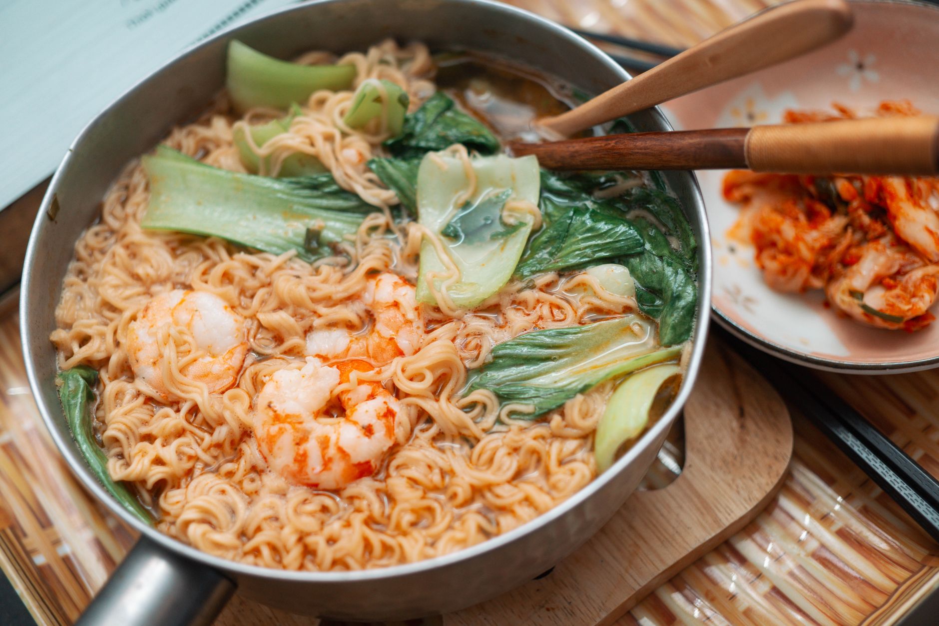 Krewetkowy ramen z bok choy i pikantnym kimchi na stole